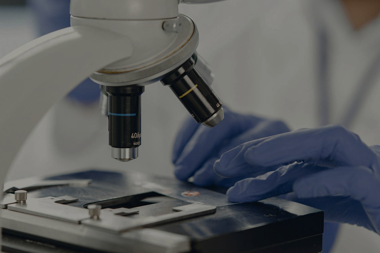 Person wearing gloves using a microscope in a laboratory setting